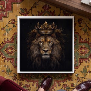 May include: A square wall art print featuring a detailed portrait of a lion with a thick mane wearing an ornate gold crown against a solid black background. The artwork is encased in a simple white frame, centered within the composition.