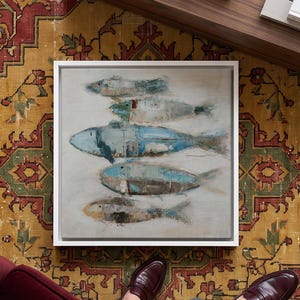 May include: A square framed wall art piece featuring a horizontal arrangement of five stylised fish in shades of blue, brown, and cream. The fish are depicted with textured, layered brushstrokes against a neutral, off-white background.