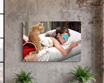 May include: A rectangular canvas print featuring a scene of a person sleeping in a bed while wearing a bright turquoise sleep mask. An orange tabby cat sits on the white bed sheets next to the person. A red blanket is visible at the foot of the bed.