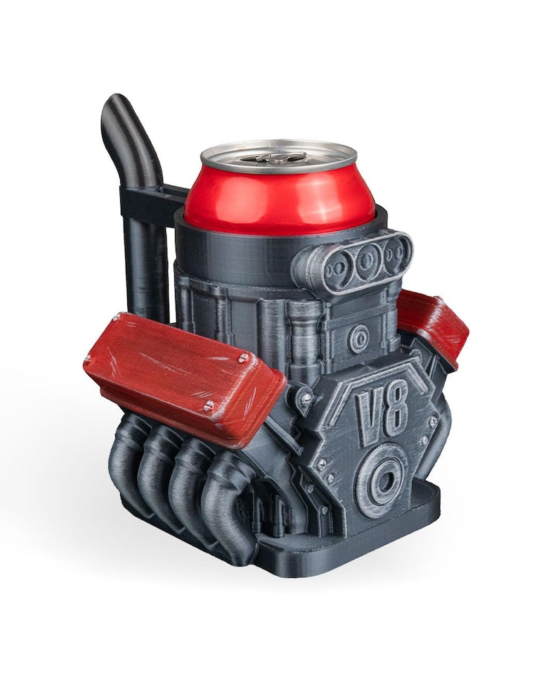 May include: A black and red V8 engine-shaped beverage can cooler featuring a metallic finish, a vertical exhaust pipe, and prominent red valve covers. The front of the engine block is embossed with the text V8, holding a red aluminum drink can.