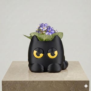 May include: A matte black cat-shaped planter featuring large, yellow, circular eyes with black pupils. The planter holds a small plant with green leaves and purple and white flowers, with the cat's paws resting at the base of the container.