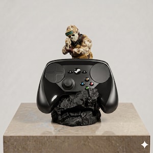 Puede incluir: Un mando de videojuego negro apoyado sobre una base oscura y dentada que simula una roca. Detr&aacute;s del mando hay una peque&ntilde;a y detallada figura de un soldado con equipo de camuflaje, m&aacute;scara de calavera y gafas, que sostiene un arma.