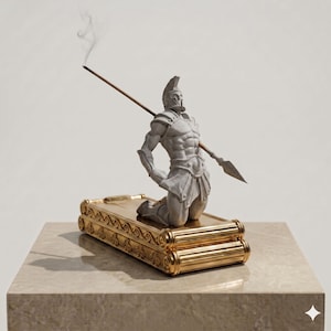 Puede incluir: Un quemador de incienso de piedra gris con una figura de guerrero arrodillado atravesado por una lanza. La figura est&aacute; montada sobre una base rectangular de color dorado con adornos de volutas y bordes estriados. Humo sale de la lanza.