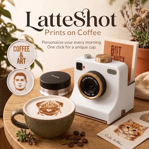 Może przedstawiać: Białe urządzenie do drukowania na kawie ze złotym pierścieniem obiektywu, z napisem LatteShot Prints on Coffee. Stoi obok zielonego kubka z wzorem mopsa w piance, czarnego okrągłego akcesorium oraz wydrukowanych kart z kotkiem i tekstem.