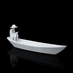 May include: A white, textured sculpture of a figure wearing a wide-brimmed hat, sitting inside a long, narrow boat. The figure is positioned at one end of the vessel, with knees bent and hands held together, appearing to look down into the boat.