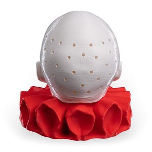May include: A white, rounded, dome-shaped object featuring a textured surface with numerous small, evenly spaced circular perforations. The object is positioned atop a vibrant, solid red, pleated, circular collar-like base with deep folds.