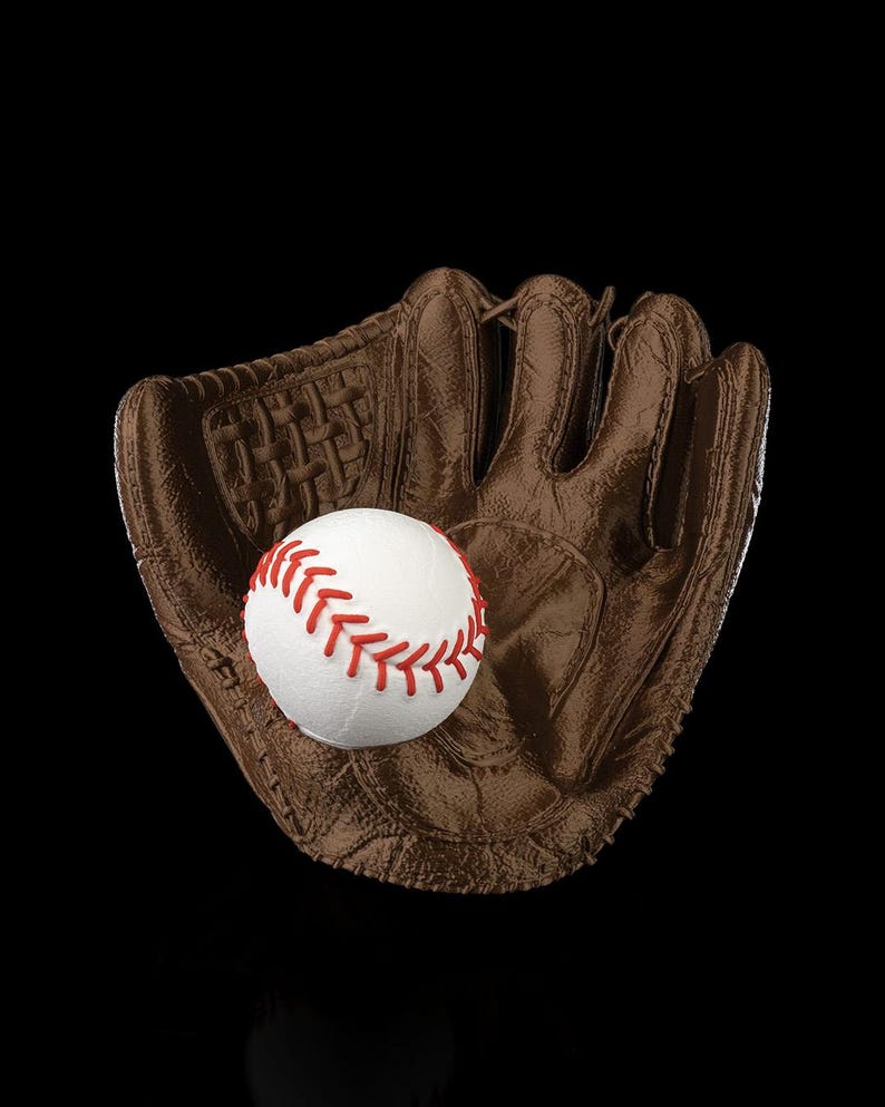 Puede incluir: Un guante de b&eacute;isbol de cuero marr&oacute;n con un dise&ntilde;o de red tejida y costuras visibles, que sostiene una pelota de b&eacute;isbol blanca con cordones rojos prominentes. El guante tiene una superficie texturizada y un bolsillo profundo.