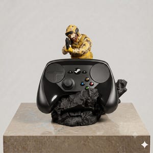 Puede incluir: Un soporte negro para mando de videojuegos con una figura de soldado en miniatura con uniforme de camuflaje beige apuntando con un arma. El mando descansa sobre una base negra de aspecto rocoso, con el logo de Steam visible en el centro.