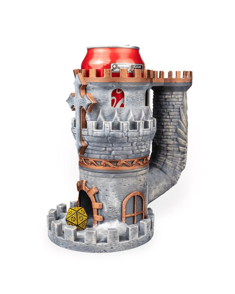 May include: A gray stone-textured castle dice tower with copper-colored accents, featuring a crenelated top, a cross emblem, and an arched doorway. A yellow twenty-sided die sits at the base, and a red beverage can is inserted into the top opening.