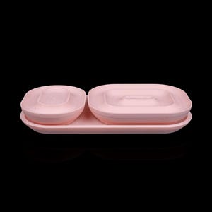 May include: A light pink rectangular tray holding two matching light pink bowls of different sizes. The smaller bowl is oval-shaped, while the larger bowl is rectangular with rounded corners. Both bowls feature a tiered, stepped interior design.