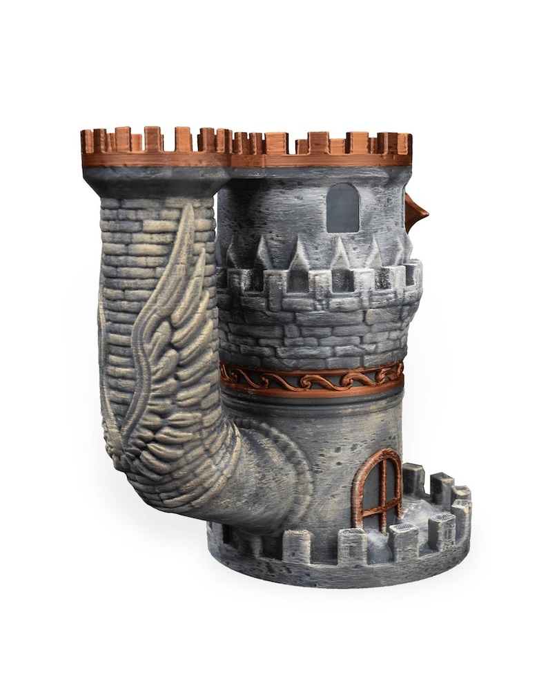 May include: A gray stone-textured dice tower shaped like a castle with copper-colored battlements and trim. The structure features a prominent wing relief on the side, a small arched window, and a base with crenelated walls for dice collection.