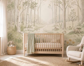 May include: A light wood crib with a sage green blanket, positioned against a wall mural featuring a watercolor forest scene with trees, a winding path, a rabbit, and a deer. A woven basket with a plush toy and a rocking chair are nearby.