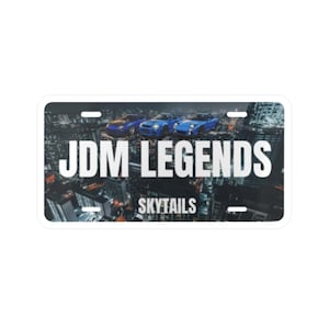 Peut inclure: Une plaque d'immatriculation rectangulaire présentant un arrière-plan de paysage urbain nocturne avec trois voitures de sport bleues. Le texte JDM LEGENDS est imprimé en grandes lettres capitales blanches au centre, avec SKYTAILS en dessous.