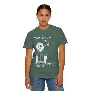 Peut inclure: Un t-shirt vert foncé avec un motif blanc représentant un panda portant un uniforme et un petit chapeau, debout derrière un comptoir avec une caisse enregistreuse. Le texte au-dessus du panda indique, Time to make the data, en blanc.