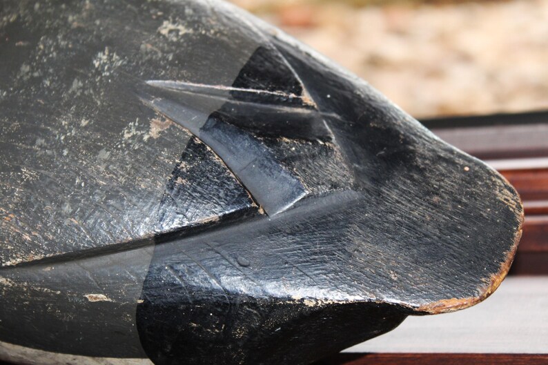 May include: A black wooden duck decoy with a carved head and a detailed paint job. The decoy has a black and gray paint scheme with a smooth finish.