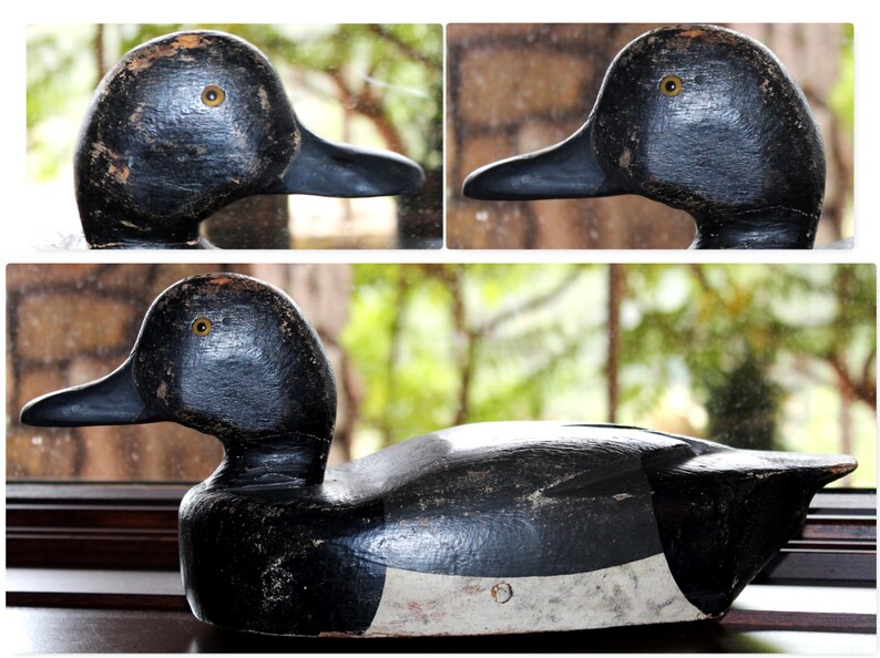 May include: A black and white wooden duck decoy with a white stripe across the chest. The decoy has a black painted finish and realistic details, including a painted eye.