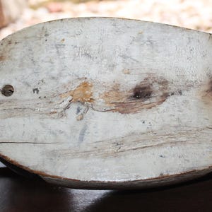 May include: A wooden duck decoy with a white painted body and a black head. The decoy has a weathered appearance and shows signs of age.
