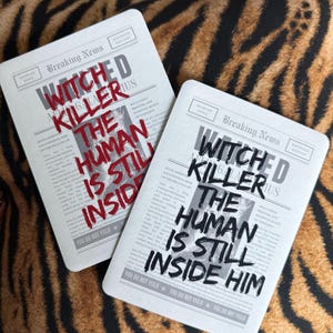 May include: Two rectangular white e-reader covers featuring a newspaper design with the text Breaking News and Adarlan News. One cover displays the red text WITCH KILLER THE HUMAN IS STILL INSIDE, while the other shows the same text in black ink.