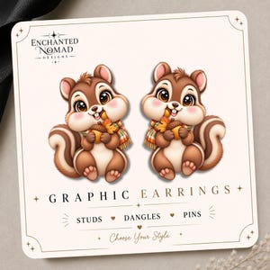 May include: A pair of brown squirrel earrings on a display card featuring the text Enchanted Nomad Designs, Graphic Earrings, Studs, Dangles, Pins, and Choose Your Style. The squirrels have large eyes, pink cheeks, and wear plaid scarves while holding acorns.