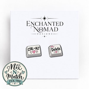 May include: A pair of white computer keyboard key earrings featuring black text. One key displays CTRL+ALT with a pink heart, and the other displays Delete with two pink hearts. The brand name Enchanted Nomad Designs is printed above the keys.