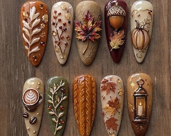 May include: A set of ten almond-shaped press-on nails featuring 3D autumn-themed designs including a white leaf, berry branches, a maple leaf, an acorn, a pumpkin, a coffee cup, a knit sweater texture, fallen leaves, and a lit lantern.