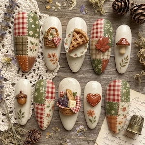 May include: A set of ten almond-shaped press-on nails featuring autumn-themed designs. The nails display patchwork patterns in red, green, and brown, alongside 3D embellishments including a picnic basket, pie slice, leaf, mushroom, acorn, and heart.