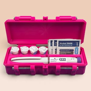 May include: A bright pink hard-shell carrying case containing a white Mounjaro KwikPen, four small round NovoFine needle caps, and three white Aero alcohol swab packets. The pen is labeled 2.5 mg dose and tirzepatide 1.17 mg/mL.