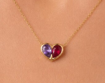 May include: A gold chain necklace featuring a heart-shaped pendant. The pendant is divided into two halves, with one side containing a purple gemstone and the other side containing a red gemstone, both set in a polished gold metal frame.