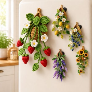 May include: Five crocheted wall hangings shaped like small baskets, each featuring different botanical designs: a large strawberry plant, a lemon branch, a blueberry cluster, a lavender sprig, and a sunflower arrangement with green leaves.