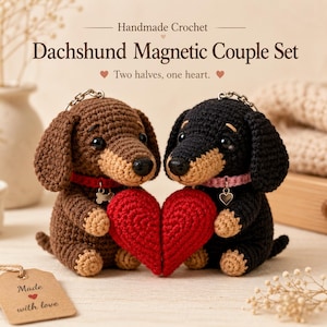 May include: Two handmade crochet dachshund keychains, one brown and one black, each wearing a collar with a charm. They are holding two halves of a red heart that connect magnetically. The text reads Handmade Crochet Dachshund Magnetic Couple Set.