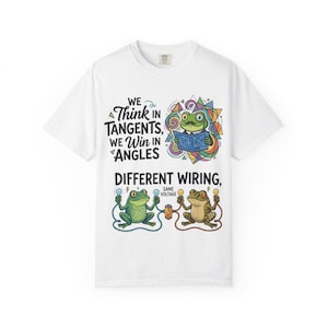 May include: A white short-sleeve t-shirt featuring a graphic print of frogs with the text: WE THINK IN TANGENTS, WE WIN IN ANGLES, DIFFERENT WIRING, SAME VOLTAGE. The design includes a frog with a moustache holding a blueprint and two frogs with wires.