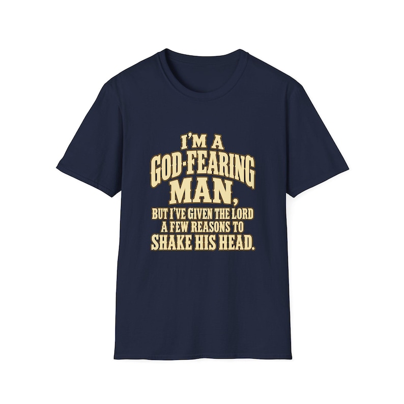 Navy short-sleeve T-shirt, front view, with ivory and gold lettering reading I’m a God-Fearing Man, But I’ve Given the Lord a Few Reasons to Shake His Head.
