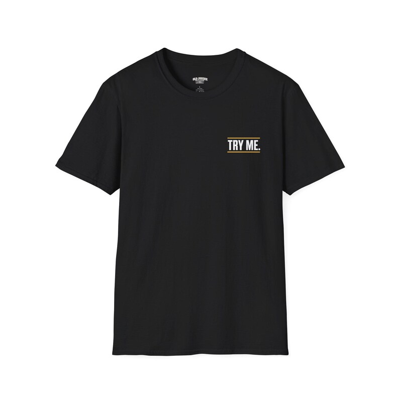 A smiling man wearing a black t-shirt with the text "TRY ME" is sitting on a white stool.