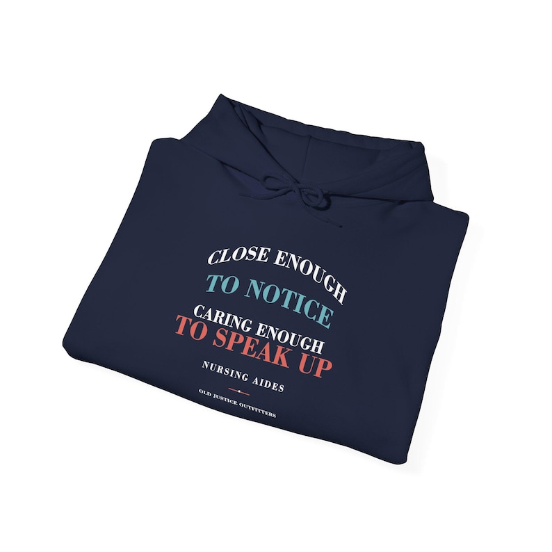 Folded navy hoodie showing the front nursing aide artwork up close.