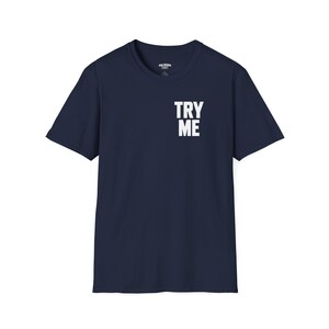 May include: A navy blue short-sleeve t-shirt featuring a crew neckline and the text TRY ME printed in bold white capital letters on the upper right chest area. The garment has a standard fit with a straight hemline and plain back.