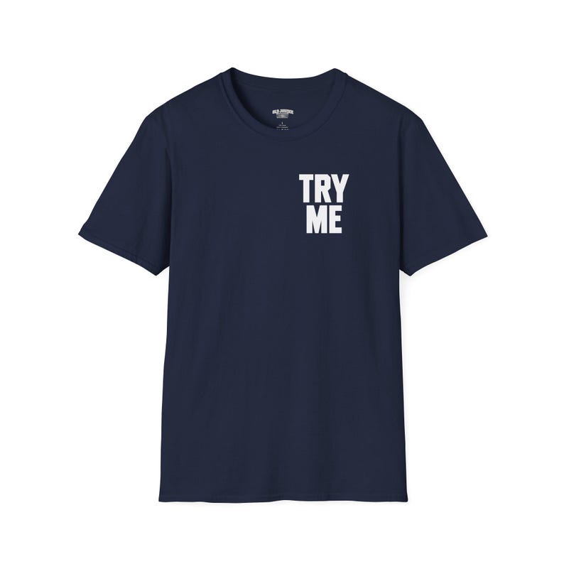 May include: A navy blue short-sleeve t-shirt featuring a crew neckline and the text TRY ME printed in bold white capital letters on the upper right chest area. The garment has a standard fit with a straight hemline and plain back.