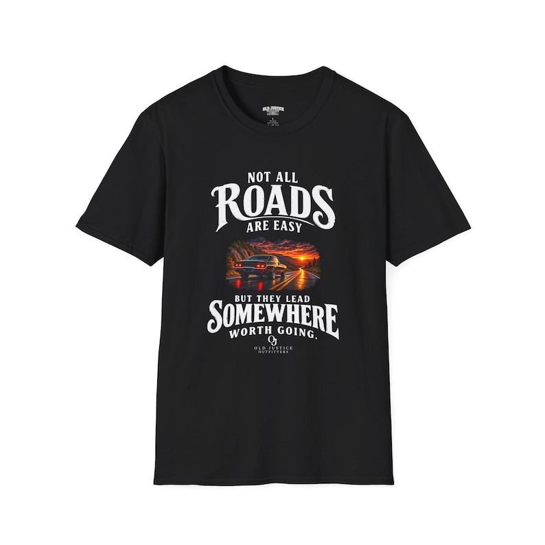 Black Not All Roads Are Easy T-shirt with white front lettering around a sunset road and car design.