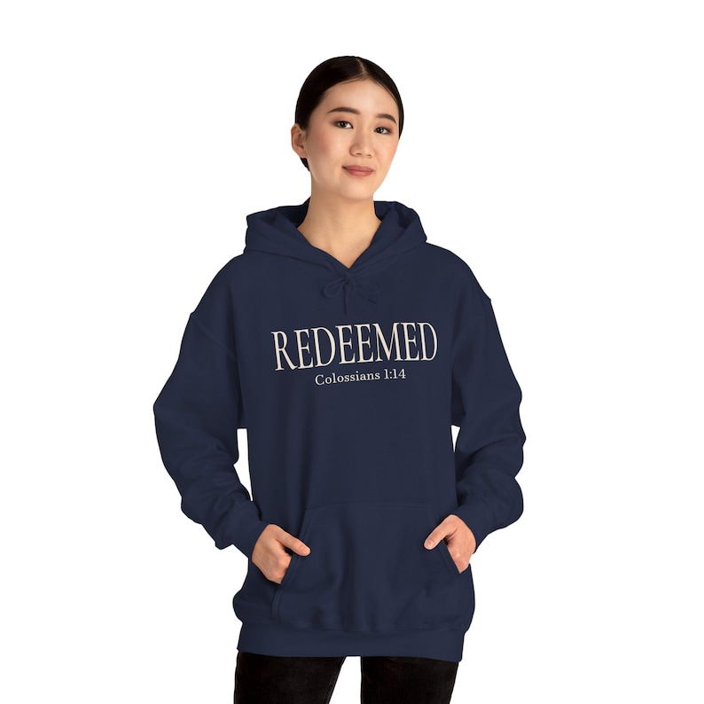 Model wearing the navy REDEEMED hoodie with the front print visible.