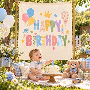 May include: A cream-colored fabric banner featuring the text HAPPY BIRTHDAY in colorful, patterned block letters. The design includes illustrations of balloons, a crown, a candle, and stars. The banner is displayed on a wooden frame.