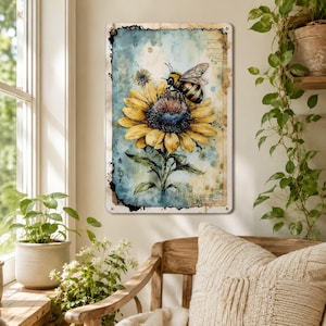 May include: A rectangular metal wall sign featuring a watercolor-style illustration of a bumblebee resting on a large yellow sunflower. The background displays a blend of blue and beige tones with subtle vintage-inspired script and ink splatter details.