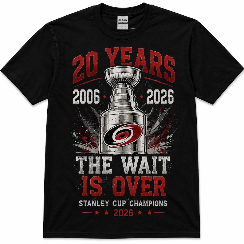 May include: A black short-sleeve t-shirt featuring a graphic of the Stanley Cup trophy in the center. Text reads 20 YEARS, 2006, 2026, THE WAIT IS OVER, and STANLEY CUP CHAMPIONS 2026. The design includes red and white accents and a team logo.