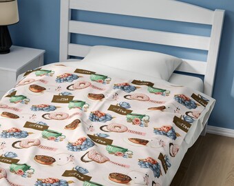 Puede incluir: Una cama individual blanca con un marco de madera blanco y una manta estampada en rosa y azul con donuts, tazas de café y las palabras "Coffee Friends".