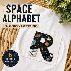 Puede incluir: Un cuadrado de tela blanca con una letra R bordada en azul oscuro, decorada con motivos espaciales que incluyen planetas, estrellas, un cohete y un OVNI. El texto dice SPACE ALPHABET EMBROIDERY PATTERN PDF y 6 LETTERS AVAILABLE.