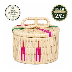 May include: A round woven basket with a lid featuring a central loop handle. The natural tan material is accented with vertical stripes of bright pink and green. The basket has a cylindrical shape with a flat base and a matching woven lid.