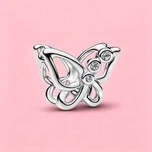 May include: A silver-toned butterfly charm featuring an openwork design with smooth, polished edges. The upper wing section is accented with three small, clear, round-cut stones set in a vertical row along the inner edge of the metal frame.