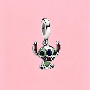 May include: A silver charm featuring the character Stitch with light green enamel on the ears and chest, dark blue enamel on the nose and eyes, and a red mouth. The charm has a polished silver finish and a circular bail for attachment to a bracelet.