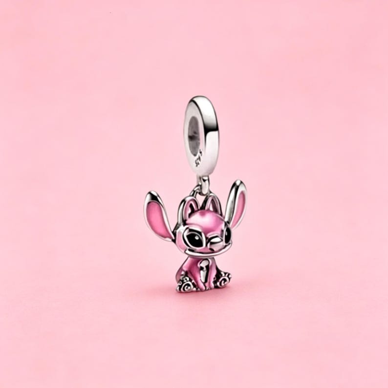 May include: A silver charm bead featuring a stylized character with large ears, pink enamel accents on the ears and body, and black enamel eyes. The charm has a circular bail at the top with the engraving S925, indicating sterling silver composition.