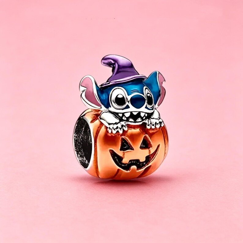 May include: A silver charm bead featuring a blue creature with large ears wearing a purple witch hat, emerging from an orange jack-o'-lantern pumpkin with a carved face. The charm has a metallic finish and detailed enamel coloring throughout.