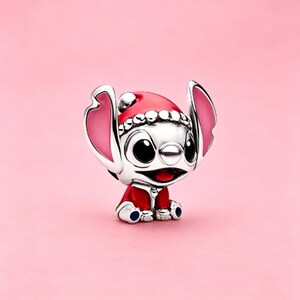 May include: A silver charm bead shaped like a character with large ears, wearing a red Santa hat with white trim and a matching red outfit. The character has black eyes, a small nose, and pink inner ears, with red enamel details on the hat and clothing.