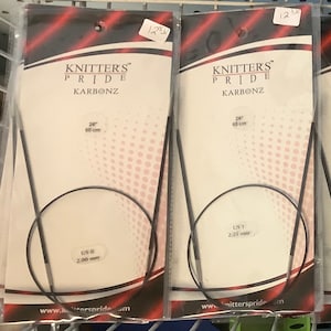 Puede incluir: Varios paquetes de agujas de tejer circulares Knitter's Pride Karbonz. Los paquetes son blancos con detalles en negro y rojo. Cada paquete muestra el tamaño y la longitud de la aguja, incluyendo 60 cm.